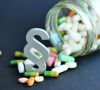 Pillen die aus Glas fallen mit Paragraphensymbol; Erfahren Sie, was GMP bedeutet, welche Ziele verfolgt werden und wie die Standards in Pharma-, Lebensmittel- und Kosmetikindustrie umgesetzt werden.