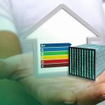 Hand mit Grafik eines Luftfilters und Haus mit Energieeffizienzklassen Skala