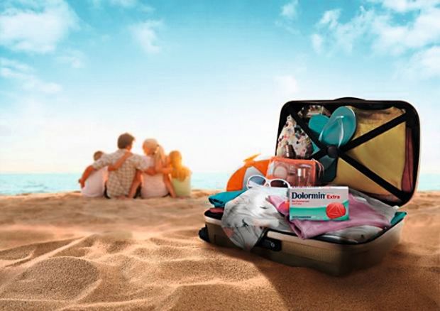 Koffer mit Medikamenten am Strand mit Familie im Hintergrund