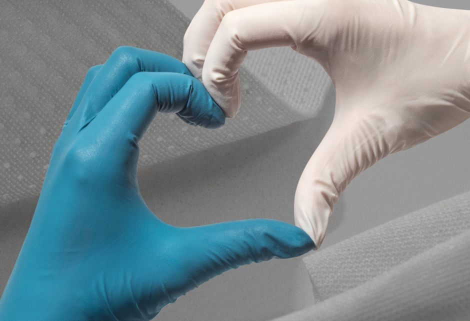Zwei Hände in Latexhandschuhen, links blau und rechts weiß, formen mit den Fingern ein Herz.