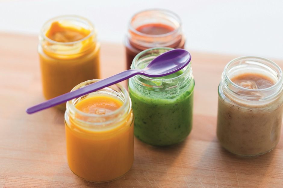 Bunte Smoothies in kleinen Gläschen mit lila Platiklöffel über einem Glas